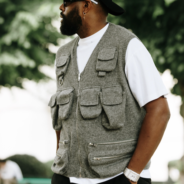 a male wearing a grey wool utility gilet with a white tshirt and sunglasses