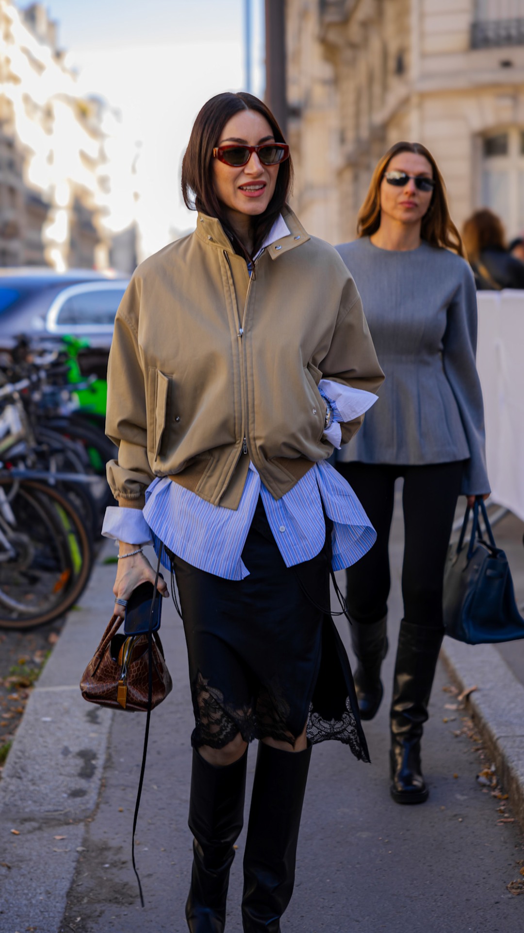 A woman with an oversized cream funnel-knecked jacket and a blue shirt used as a layering piece underneath