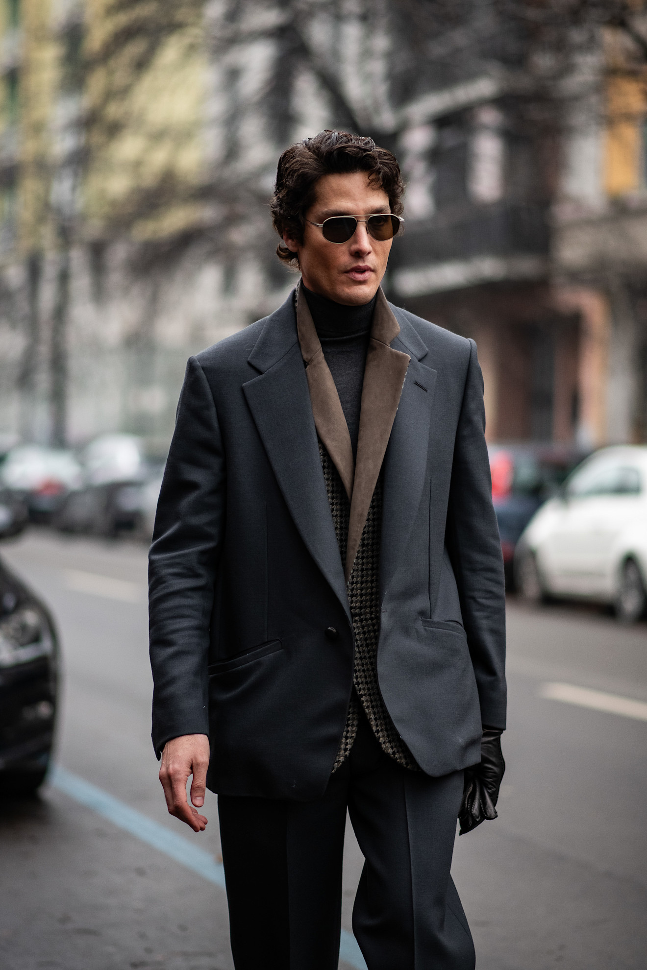 A man with a grey oversized suit with a brown undercoat layer and black knitwear baselayer